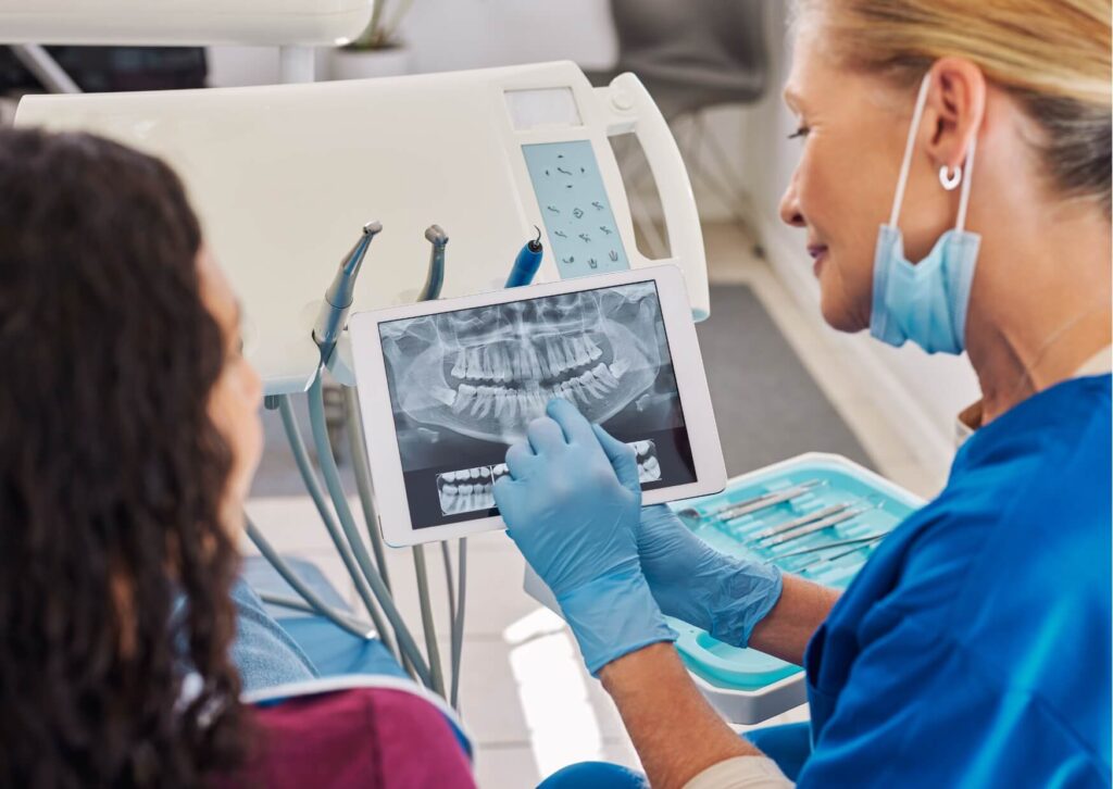 Orthodontist reviewing dental X-rays with a patient while discussing treatment options for fixing an underbite with braces.