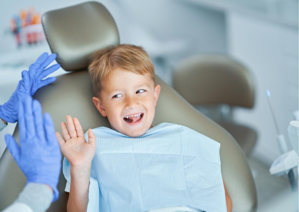 Young child smiling in a dental chair during a pediatric dental visit, where a dental spacer may be recommended to preserve space for incoming permanent teeth.