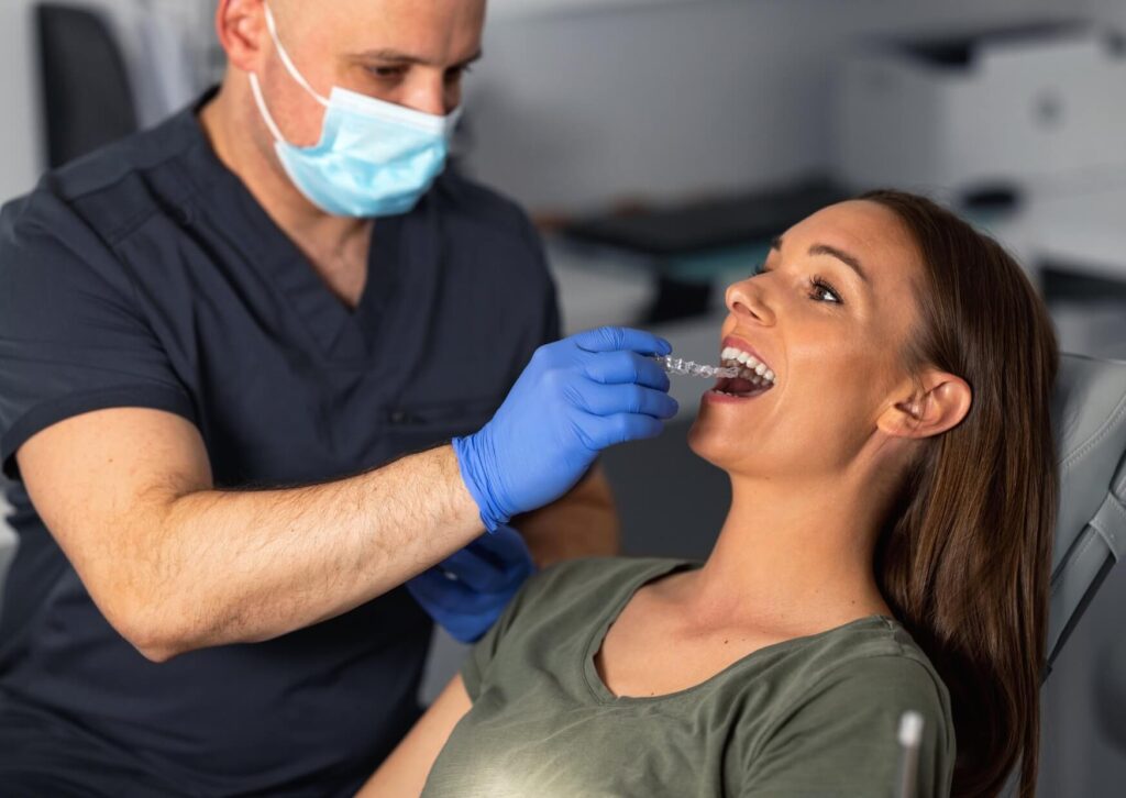 Orthodontist fitting clear aligners for an adult patient as an alternative to traditional adult braces.