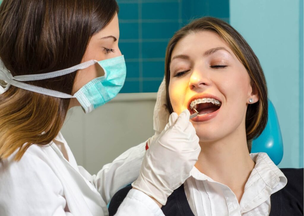 Orthodontist examining a patient with braces during a checkup to monitor tooth movement and changes in face shape throughout treatment.