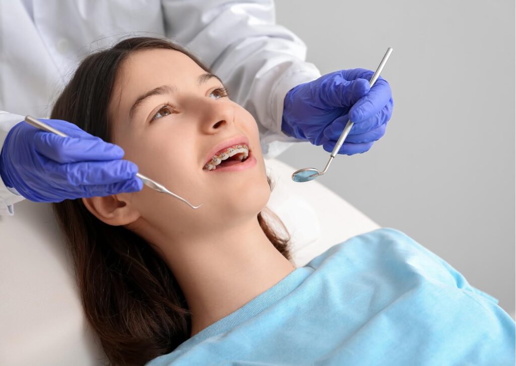Teen patient wearing Damon braces during an orthodontic appointment to evaluate treatment progress and estimated treatment time.